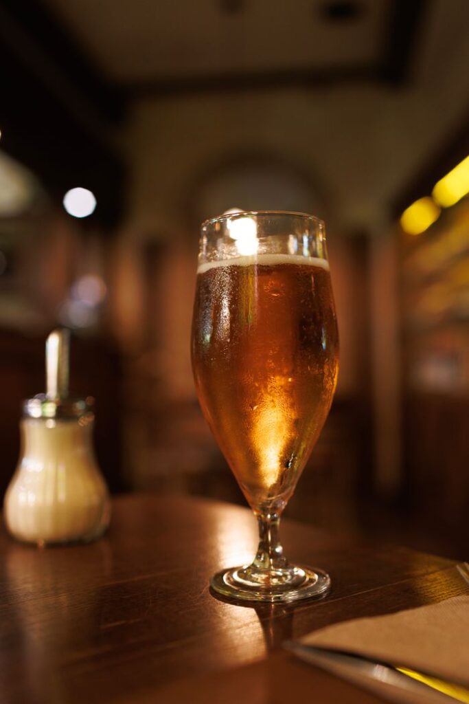 A refreshing pint of amber beer served chilled on a wooden table in a cozy pub setting.